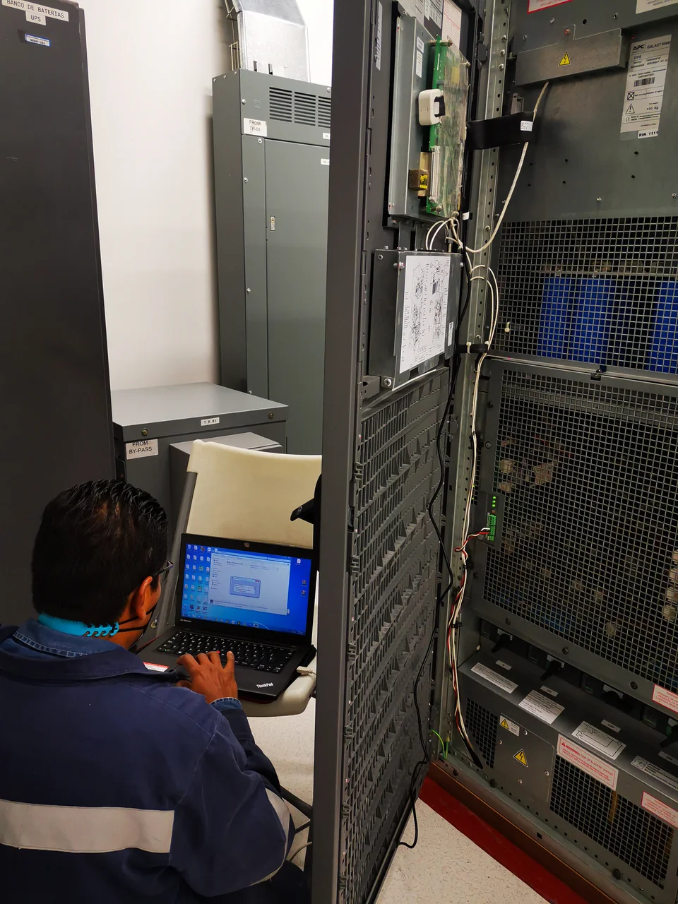 Técnico realizando diagnóstico con una computadora portátil junto a un sistema UPS abierto